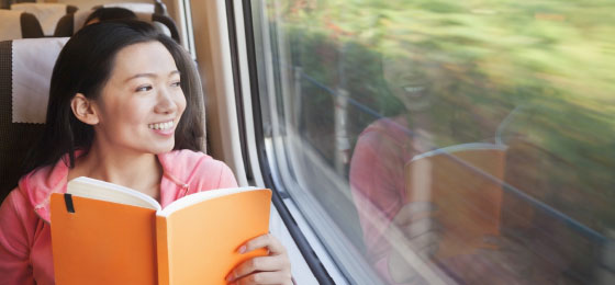 asian woman with book on a train
