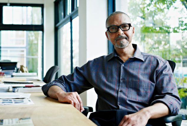 Man sits casually at corporate desk, looking at the camera