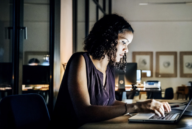 Woman works on her laptop at desk late at night