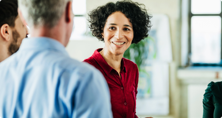 A smiling woman looks at her colleague in a team meeting