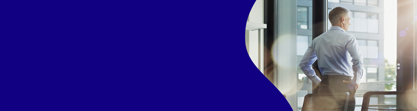 Businessman standing in a modern office looking out of the window