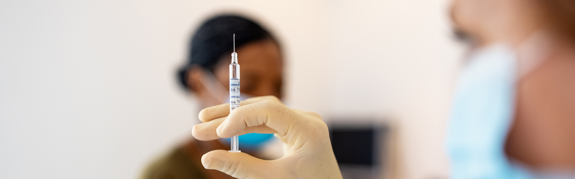 Doctor wearing mask holding a vaccine