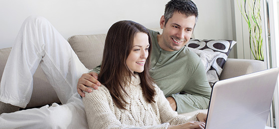 man and woman at home looking at a computer screen